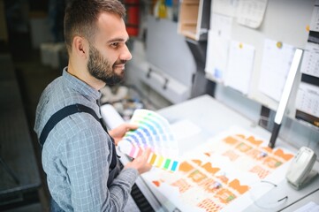 Typographer standing with color swatches at the printing manufacturing