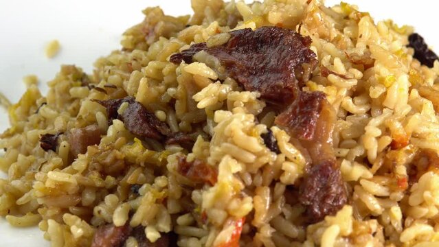 Pilaf rotates on a plate. Traditional East Asian dish with chickpeas, barberries, cumin, long grain rice and lamb