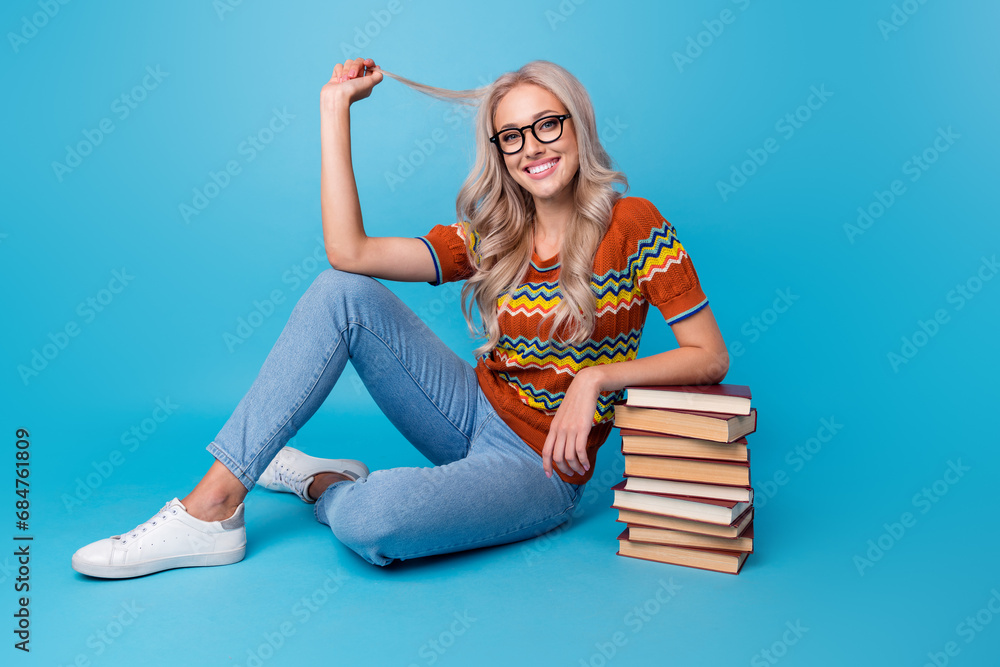 Poster full length photo of sweet positive girl dressed print shirt eyewear enjoying book pile stack isolat