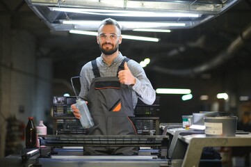 Man working in printing house with paper and paints