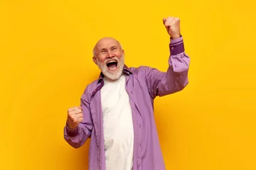Garden poster Old door old bald grandfather in purple shirt celebrates victory with his mouth open on yellow isolated background