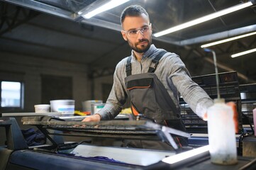 Print worker trying to fix the problem on computer to plate machine in printing shop