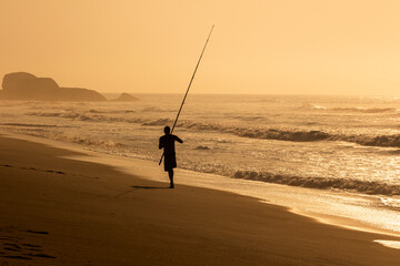 Silhueta de pescador, hora dourada, amanhecer na praia