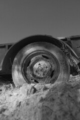 Old flat tire in black and white on aged trailer, vertical view closeup.