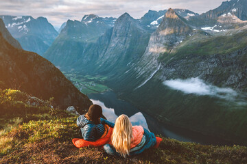 Romantic couple in sleeping bags enjoying bivouac in Norway mountains, friends man and woman hiking...