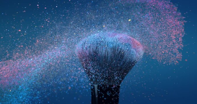Super slow motion macro of make up brushes with flying colorful cosmetic product powder dust particles splash explosion isolated on soft dark background.