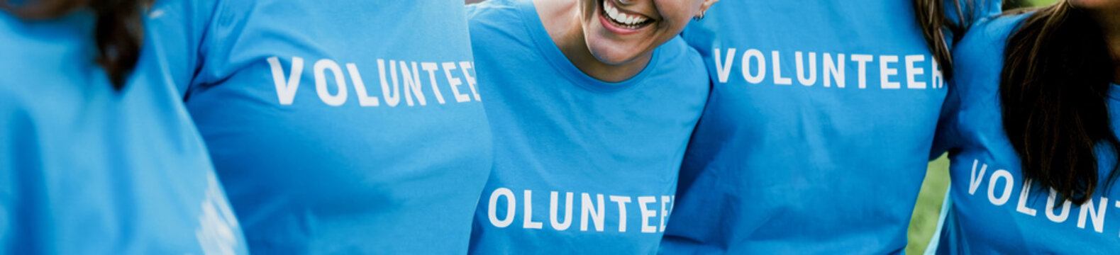 Happy group of volunteer people celebrating together outdoors. Teamwork and charity support concept.
