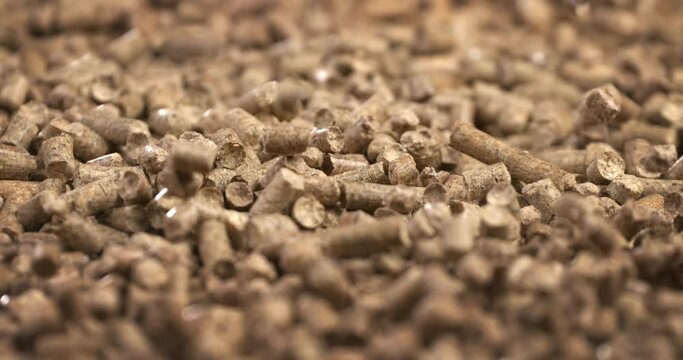wood heating; falling wood pellets against black background. slow-motion  about small pieces of compress wood and renewable energy sources for warm houses and hot water at home.