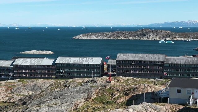 Ocean, icebergs and Greenland settlement. Greenland arctic village Ilulissat. Colorful inuit houses. Greenland polar landscape. Travel to the Arctic Circle. Climate change, global warming.