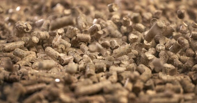 wood heating; falling wood pellets against black background. slow-motion  about small pieces of compress wood and renewable energy sources for warm houses and hot water at home.