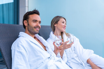 Relaxed couple in bathrobe drinking wine in a hotel terrace