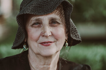 Portrait of a happy elderly woman 65 - 70 years old in a straw hat on the background of nature,...