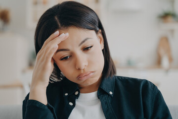 Woman feeling stressed with hand on forehead, looking down