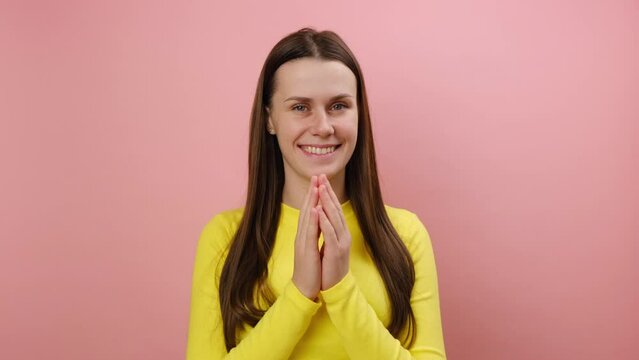 Tricky cunning smiling young caucasian woman standing looking at camera, planning something, pranking somebody, wearing yellow sweater, posing isolated over pink color background wall in studio