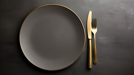 Dark plate with with golden cutlery on black background