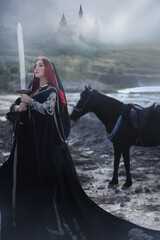 A warrior girl in a black oriental costume on a black horse with a katana in her hands.