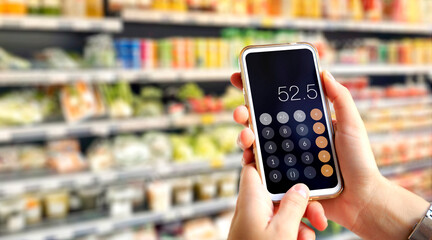 Calculator on mobile phone screen in customer's hands. Young woman does accounts in the supermarket using calculator.