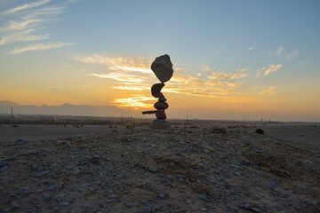 a rock stack on the ground at sunset with people walking by