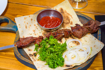 Barbecue on a skewer with tomato sauce, onions and herbs. 