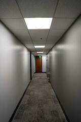Empty long office hallway with fluorescent lights.