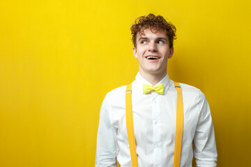 funny guy in bow tie and suspenders looks in surprise to the side with his mouth open on yellow...