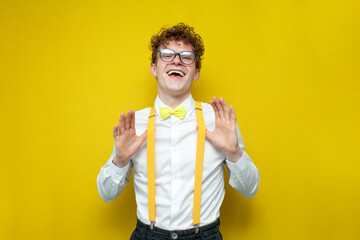 confident cheerful guy in festive outfit and glasses rejoice, nerd student in bow-tie shirt and suspenders - obrazy, fototapety, plakaty
