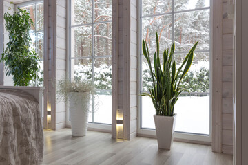 Cozy winter atmosphere. Spacious bedroom with floor-to-ceiling window overlooking snowy landscape