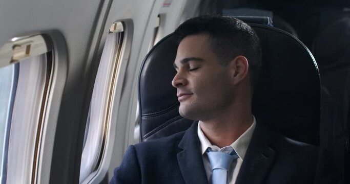 Close up of young businessman is looking outside window of aircraft while flying at airplane first class for business travel to meet his partners for discuss new project and collaboration.