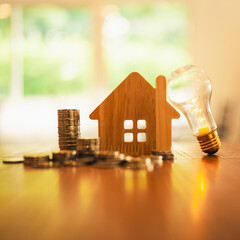 Wood house model and row of coin money with a light bulb . Money management, financial plan,...