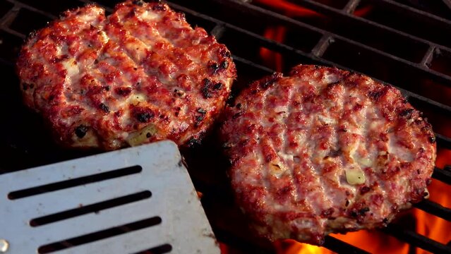 metal spatula turns a hamberger cutlet over the fire