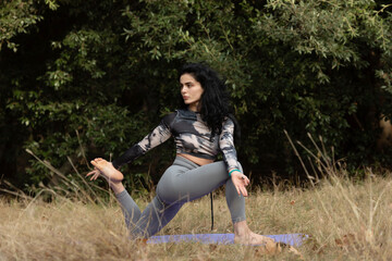 Pretty woman doing yoga exercises in the autumn park.  A woman practices yoga alone in the forest.