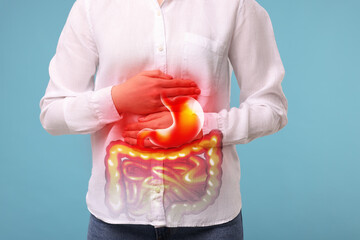 Woman suffering from stomach ache on light blue background, closeup. Illustration of unhealthy...
