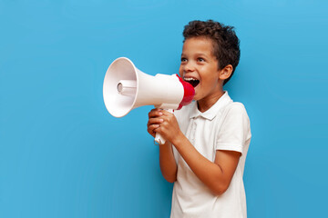 African-American boy in white polo announces information into megaphone on blue isolated background