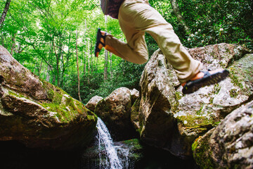 A man jumps between two boulders while fly fishing in  Pisgah National Forest, North Carolina