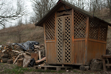 View of a wooden gazebo and pile of a stacked logs in a rainy day