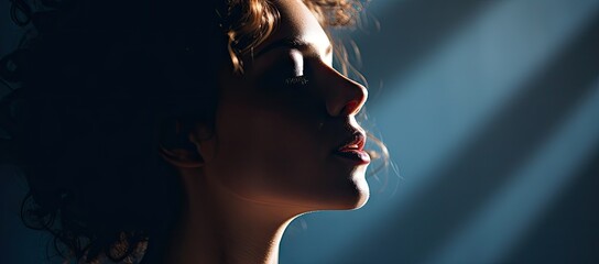 a close up of a woman's face with a light coming from behind her and her hair blowing in the wind.