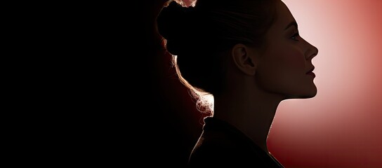  a silhouette of a woman with her hair in a pony tail, against a red and black background, with the image of a woman's head in profile.