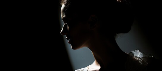  a close up of a woman's face in the dark with a light shining on her right side of her face.
