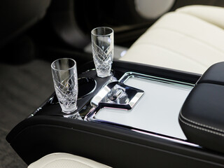 crystal glasses for champagne in the armrest in the back row of a luxury car