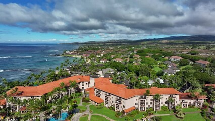 Aerial Kauai Hawaii beach condominium homes shoreline. Expensive luxury homes, resort, condominium and golf club near coast. Recreation and tourism.  Economy tourism based. Tourist enjoy warmth.