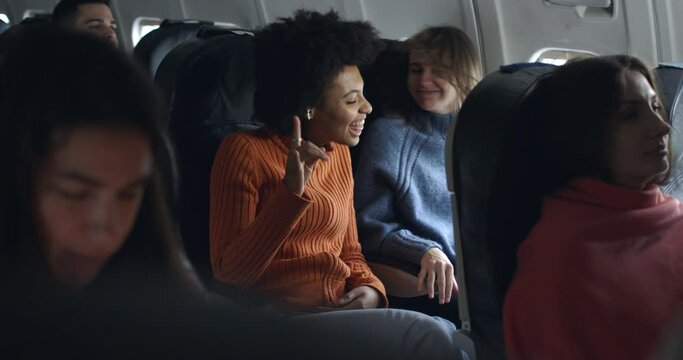 african girl and blonde friend in airplane have a humor moment with hard rock metal music and having fun together in friendship during the flight from the distant airport.