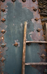 wooden ladder leaning against rust and blue rusty metal grunge grungy antique old weathered textured background or backdrop empty space for type vertical image antique blue and rust colored metal