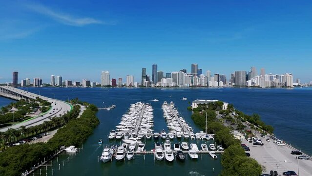 Drone view on Virginia Key coastline and rich Miami disrtict opposite. Stunning area for recreation with luxury boats and riding cars on bridge roadway across ocean.