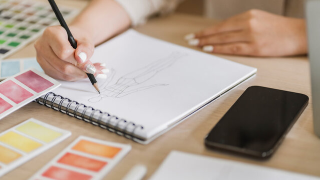 Close up Creative fashion designer atelier sketching on drawing book in studio.