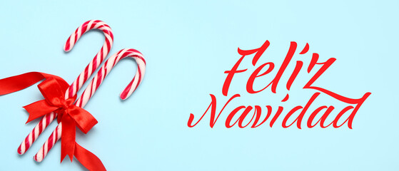 Sweet candy canes and text FELIZ NAVIDAD (Spanish for Merry Christmas) on light blue background