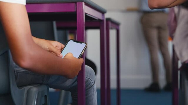 Close up of male secondary or high school pupil looking at mobile phone cheating during lesson - shot in slow motion