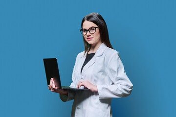 Woman medical scientist, pharmacist in white coat using laptop on blue background