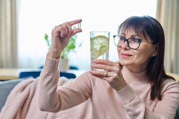 Middle-aged woman taking dietary supplement, fish oil capsule, omega 3