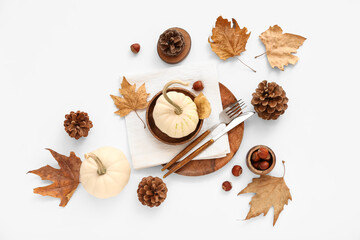 Autumn table setting with pumpkins, chestnuts and dried leaves on white background