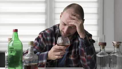 A depressed man sniffs alcohol in a glass and is disgusted. Alcohol addiction concept.
